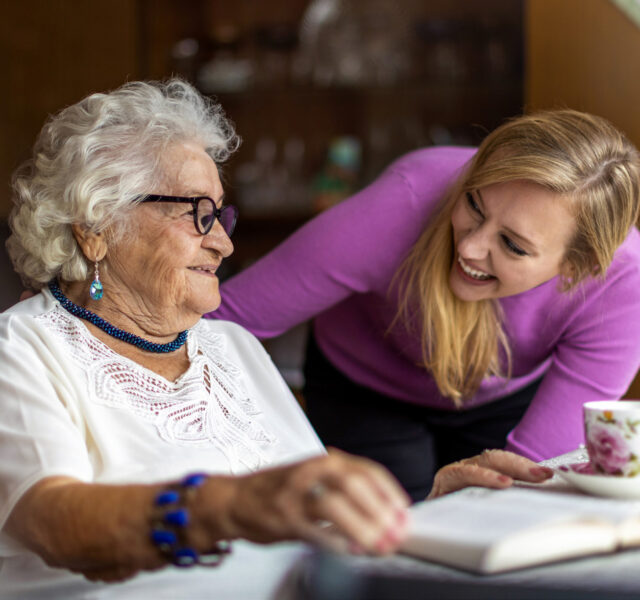 Younger lady laughing with an older lady at a table