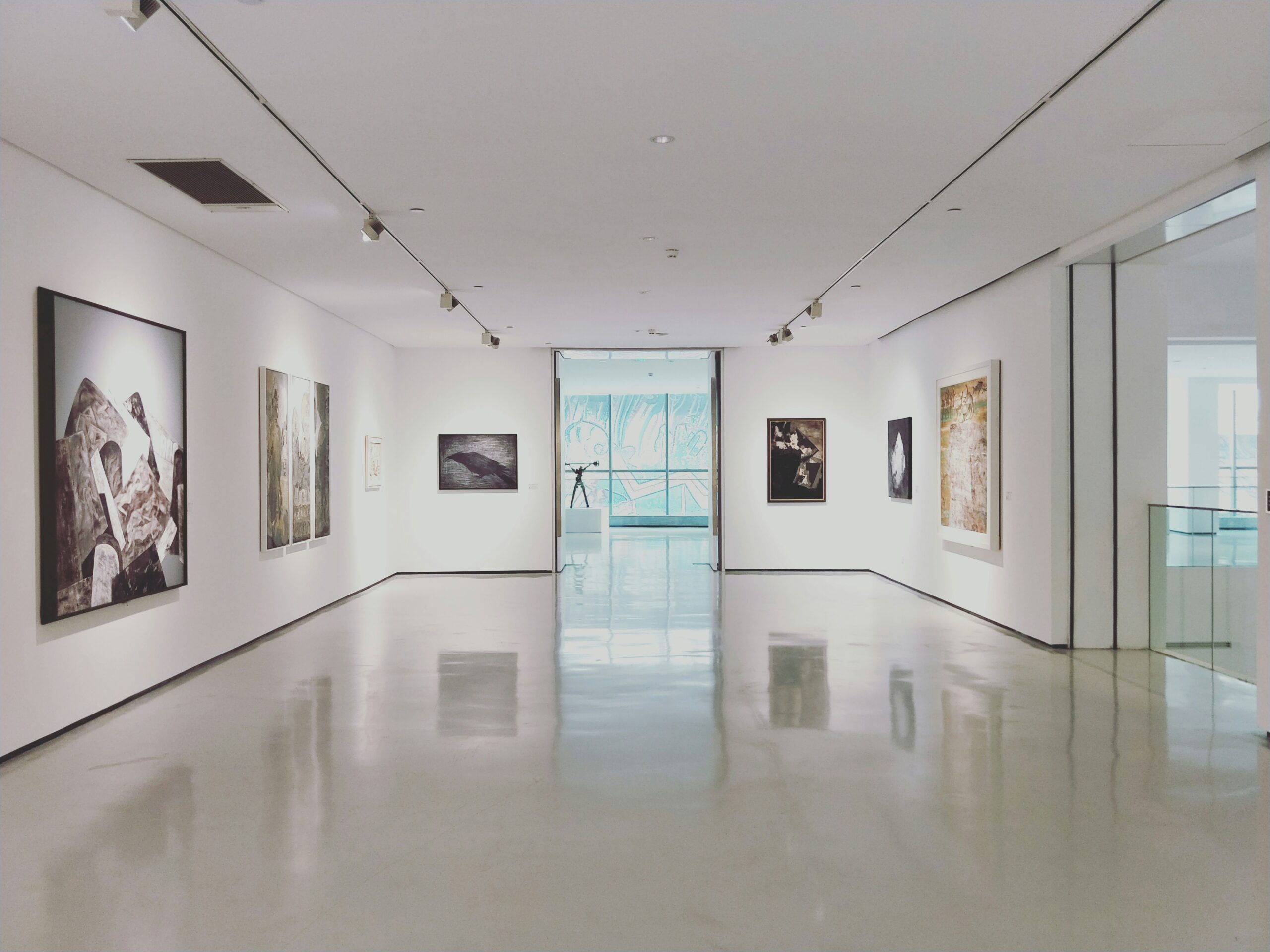 Modern white-walled art gallery in Beeston with sculptures and paintings displayed under natural sunlight.